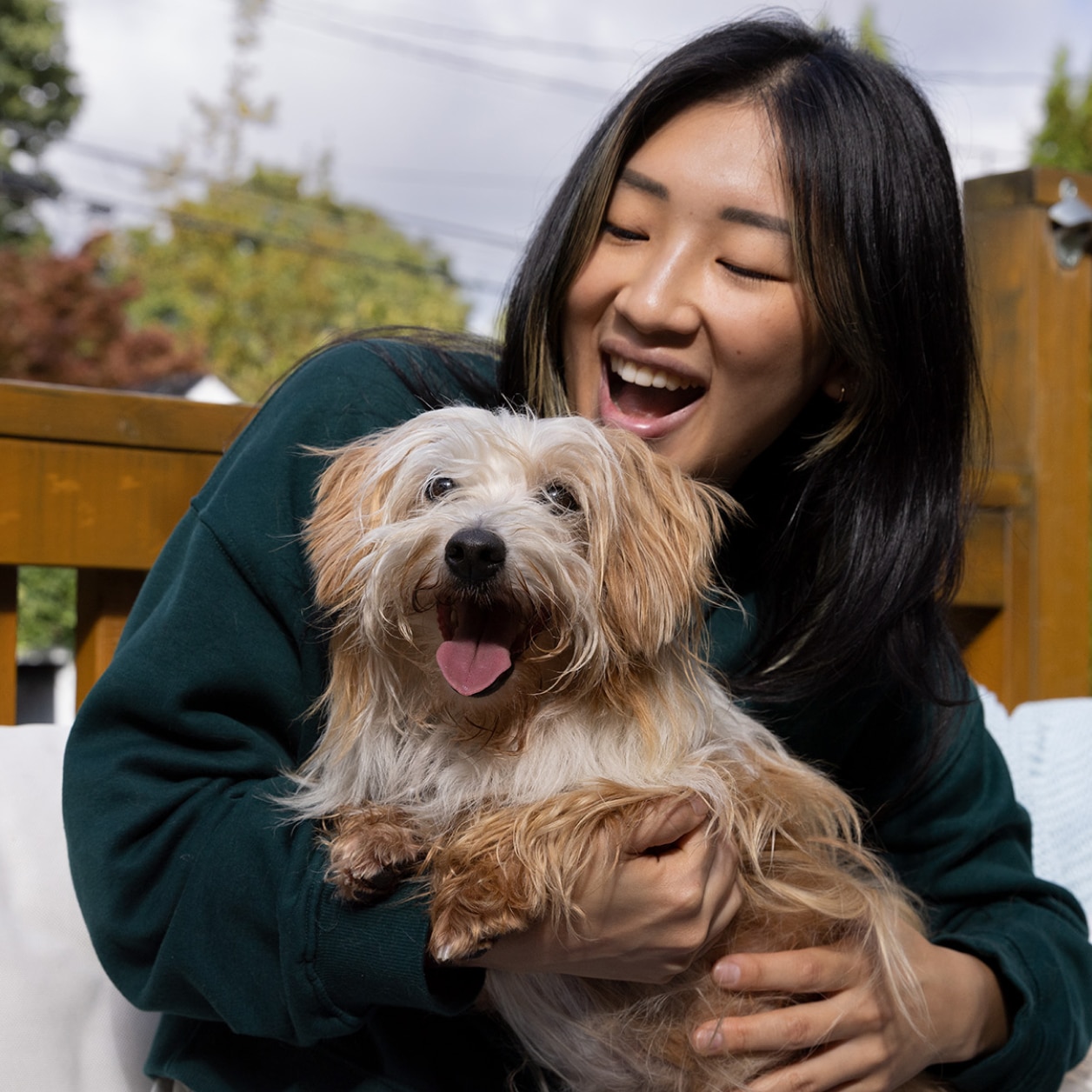 Eine Frau mit einem glücklichen kleinen Hund in ihren Armen
